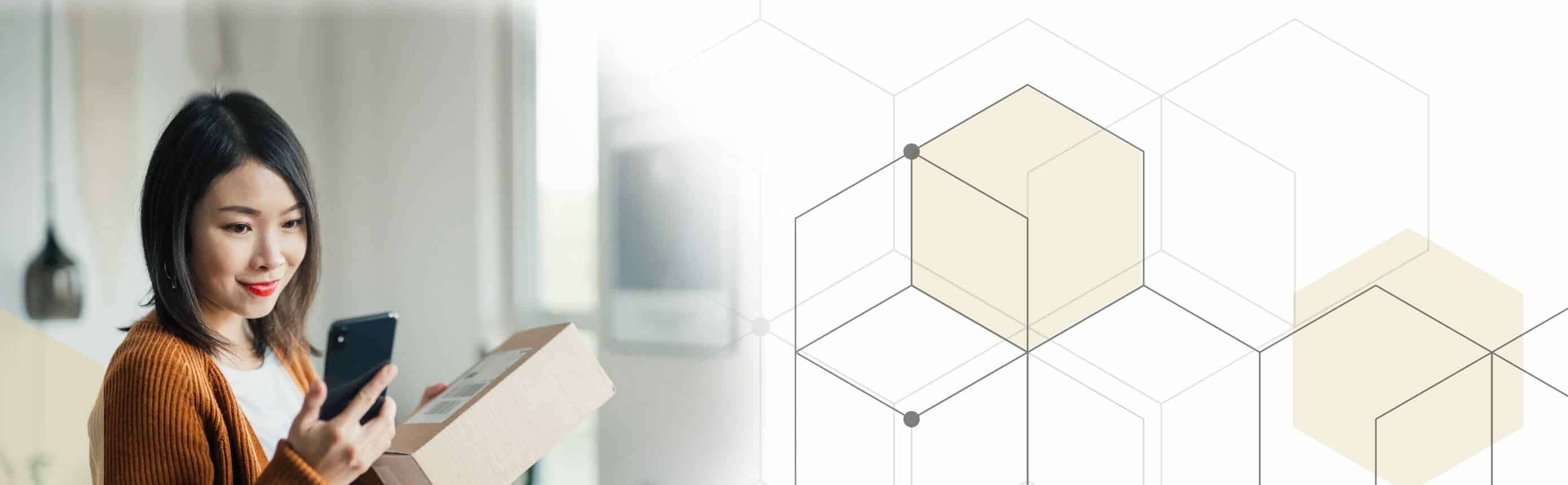 woman holding box and looking at cell phone